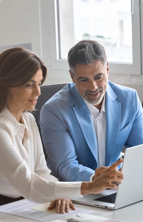 Two people sitting at a table, pointing at a computer screen